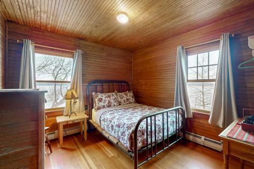 una camera da letto con un letto in una stanza con pareti in legno di Wildberry Cottage a Bomoseen
