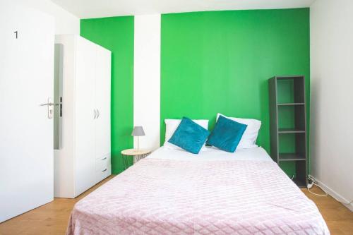 a green bedroom with a bed with two blue pillows at Colocation de luxe à Tourcoing avec jardin in Tourcoing