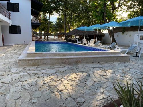 a pool with chairs and umbrellas next to a building at Hotel Zapata in Boca Chica