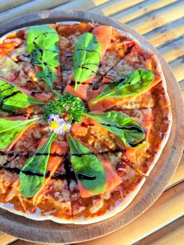 a pizza with leaves on a plate on a table at Three Trees Samui Resort - Sarocha Villa in Lamai