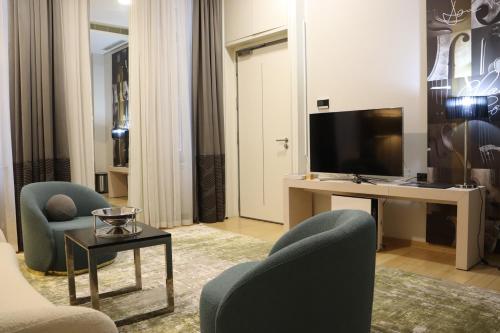 a living room with a tv and two chairs and a table at Zepter Hotel Belgrade, member of Zepter Hotels in Belgrade