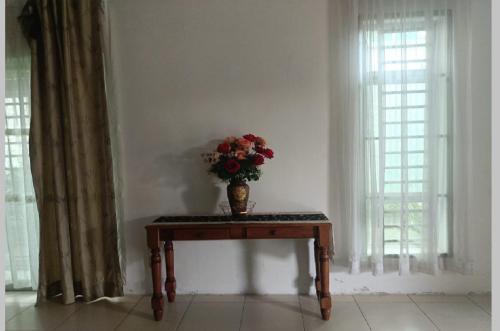 a vase of flowers on a table in a room with windows at Juliana Homestay in Jitra