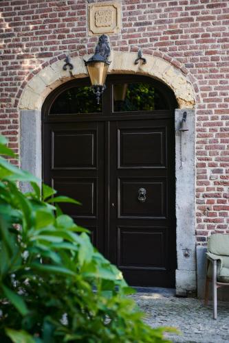 a black door in a brick building with a lamp at Broekemmolen - Nature getaway & green spot in Bilzen