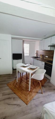une cuisine avec une table blanche et deux chaises blanches dans l'établissement 2 - Dagobert Cosy Studio Centre, à Perpignan
