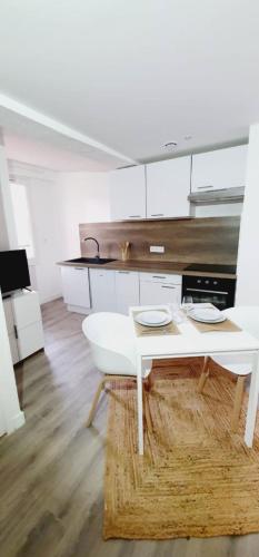 une cuisine blanche avec une table blanche et un comptoir blanc dans l'établissement 2 - Dagobert Cosy Studio Centre, à Perpignan