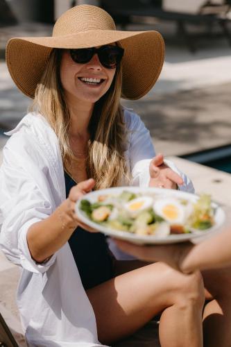 a woman in a hat holding a plate of food at Mas de la Fouque - Hôtel & Spa in Saintes-Maries-de-la-Mer