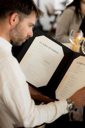 a man sitting at a table reading a book at Mas de la Fouque - Hôtel & Spa in Saintes-Maries-de-la-Mer