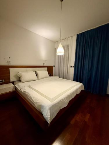 a bedroom with a large white bed with blue curtains at Suite 419 TQ Plaza in Budva