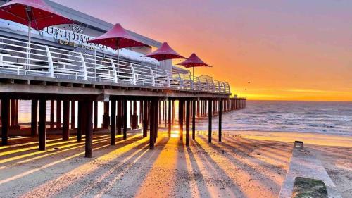 a pier with umbrellas on the beach at sunset at Modern 2 Bedroom Apartment with Sea view in Felixstowe