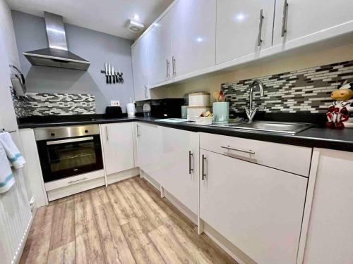 a kitchen with white cabinets and a sink at Modern 2 Bedroom Apartment with Sea view in Felixstowe