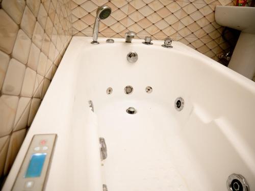 a white bath tub with a faucet in a bathroom at Sleeps8-Parking-Jacuzzi-WiFi-AirCon in Iseri-Oke