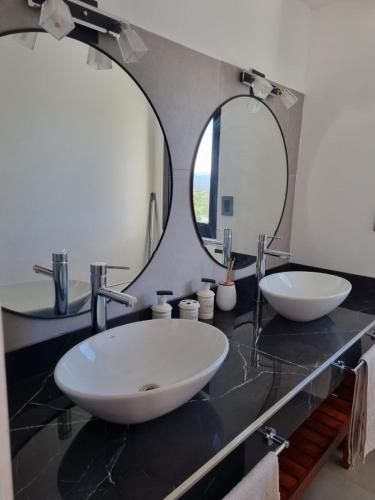 a bathroom with two sinks and a large mirror at Escondite Serrano in Villa Giardino