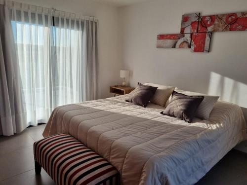 a large bed in a room with a large window at Escondite Serrano in Villa Giardino