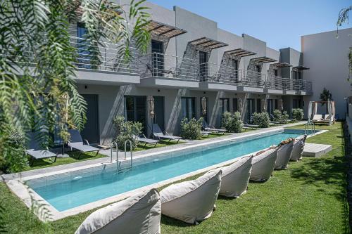 a hotel with a swimming pool and chairs next to a building at NEK Suites - Adults Only in Chania Town