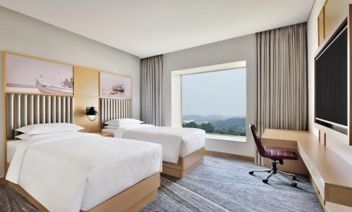 a hotel room with two beds and a large window at Four Points by Sheraton Kochi Infopark in Cochin