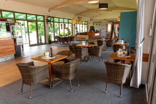 a restaurant with wooden tables and chairs and windows at Vulkán Wellness Hotel & Camping in Celldömölk