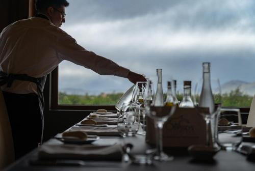 a man standing at a table with wine glasses at Río Serrano Hotel + Spa in Torres del Paine