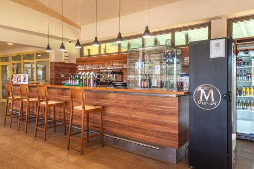 a bar with a row of stools in a restaurant at Vulkán Wellness Hotel & Camping in Celldömölk