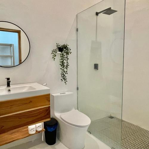 a bathroom with a toilet and a glass shower at The Peak Surf House in Huu