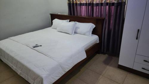 a bed with white sheets and pillows in a room at Jakara Avenue Hotel- Tamale in Kyanshiogo