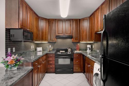 a kitchen with wooden cabinets and a black refrigerator at Broadway Plaza, Trademark Collection by Wyndham in Rochester
