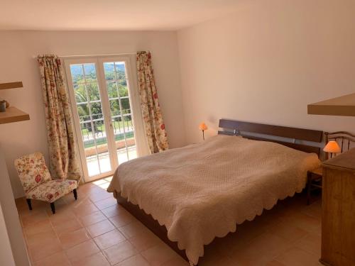 une chambre avec un lit, une fenêtre et une chaise dans l'établissement Villa Les Vignes, à Le Revest-les-Eaux