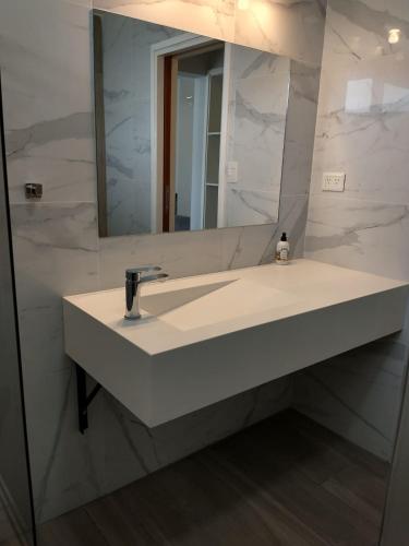 a bathroom with a white sink and a mirror at Apart Hotel City Bell in City Bell