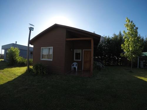 a small house with a chair in the yard at Spa, piscina y cabañas Tierra Mar in La Montaña