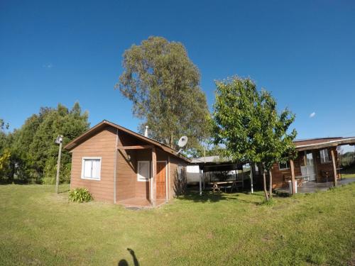 a small house in a field next to a tree at Spa, piscina y cabañas Tierra Mar in La Montaña