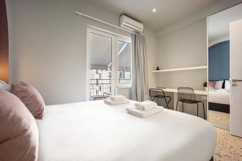 a bedroom with a large white bed and a desk at Arches Apartments in Athens