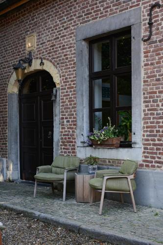 two chairs and a table in front of a building at Broekemmolen - Nature getaway & green spot in Bilzen