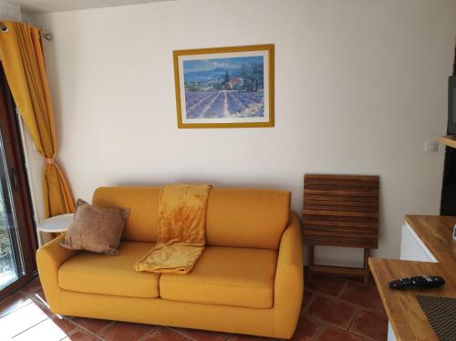 - un canapé jaune dans le salon avec une photo sur le mur dans l'établissement Le Loft au fil de l'eau, à Saulzoir