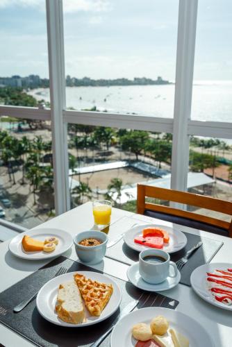 a table with plates of food and a view of the ocean at Hotel Brisa Praia Pajuçara in Maceió