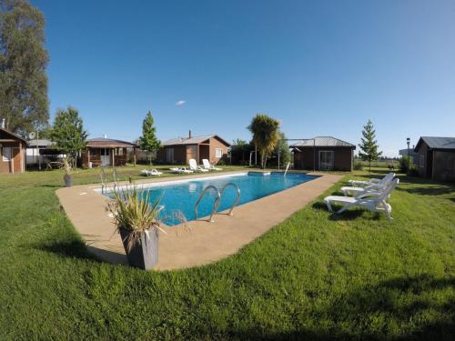 a swimming pool in a yard with two white benches at Spa, piscina y cabañas Tierra Mar in La Montaña
