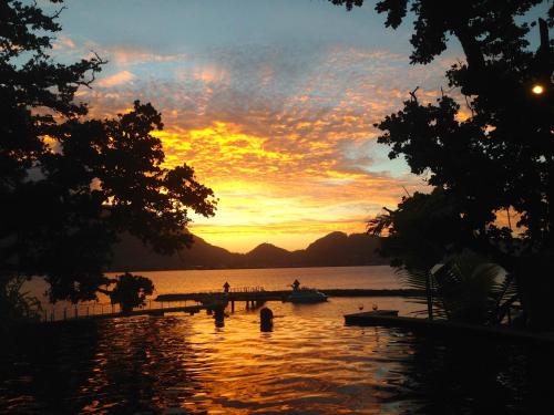 a sunset over a lake with a pier and a boat at Cerf Island Resort in Cerf Island