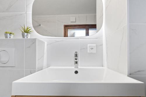 a white bathroom with a sink and a mirror at Bel appartement avec vue alpine in Nendaz
