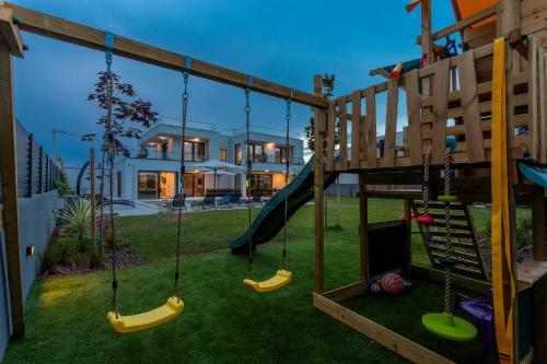 Un patio trasero con un parque infantil con columpios en 5 Star Luxury Villa78, en Banjole