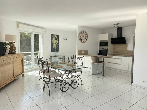 une cuisine et une salle à manger avec une table et des chaises en verre dans l'établissement PLEIN SUD 2 VUE MER, à Narbonne-Plage