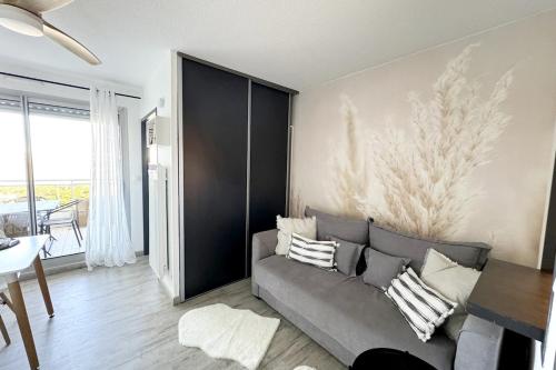 un salon avec un canapé gris et une table dans l'établissement Studio, terrasse, wifi, pkg, La Grande Motte, à La Grande Motte