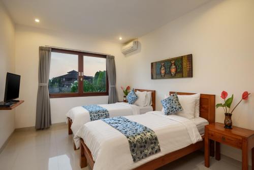 two beds in a room with a window at Echo Beach Townhouses in Canggu