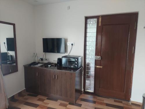 a room with a door and a microwave on a counter at Sapphire Stayss in Yelagiri