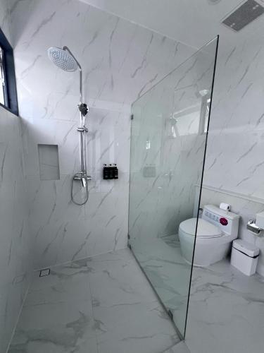 a white bathroom with a shower and a toilet at Three Trees Samui Resort - Sarocha Villa in Lamai