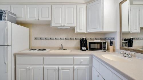 a white kitchen with a sink and a microwave at Daytona Beach Getaway with Direct Ocean Views in Daytona Beach