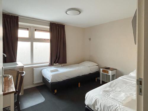 a hotel room with two beds and a window at VISSERSLUST Rooms, Apartments and Houseboats in Vinkeveen