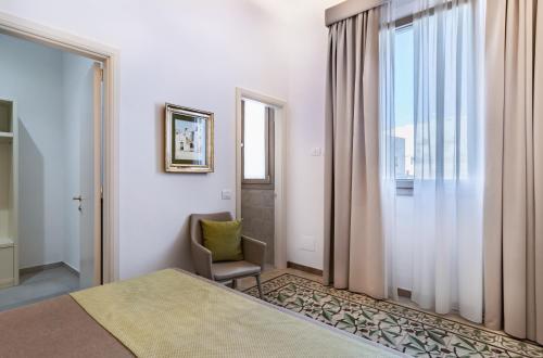 a bedroom with a bed and a chair and a window at Palazzo San Lazzaro - Jacuzzi Rooms & Suites Lecce Selection in Lecce
