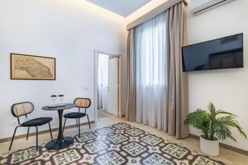 a living room with a table and chairs and a tv at Palazzo San Lazzaro - Jacuzzi Rooms & Suites Lecce Selection in Lecce