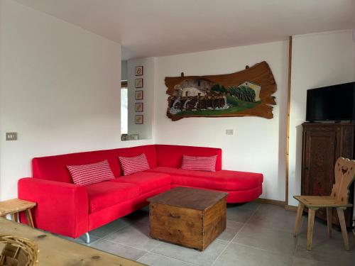 ein rotes Sofa im Wohnzimmer mit einem TV in der Unterkunft Appartamento TEMELIN in Bormio