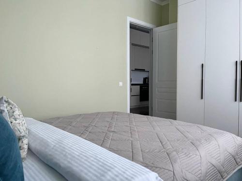 a white bedroom with a bed and a closet at GreenLine Terra in Astana