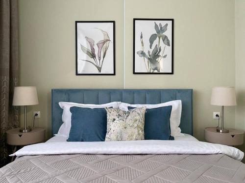 a bedroom with a blue bed with three pictures on the wall at GreenLine Terra in Astana