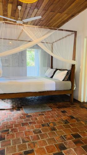 a bedroom with a bed with a mosquito net at Whispering House in Tangalle